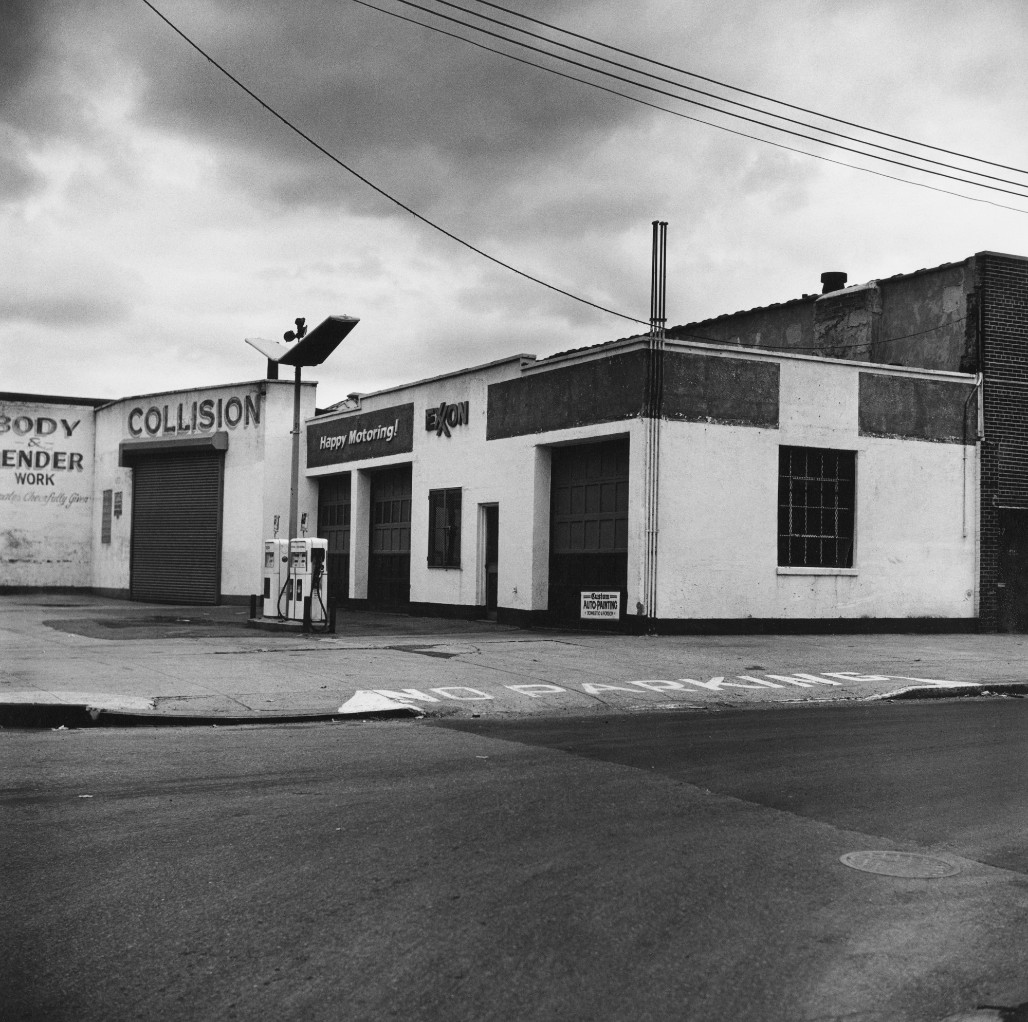Black and white photograph of the exterior of a gas station during early morning hours