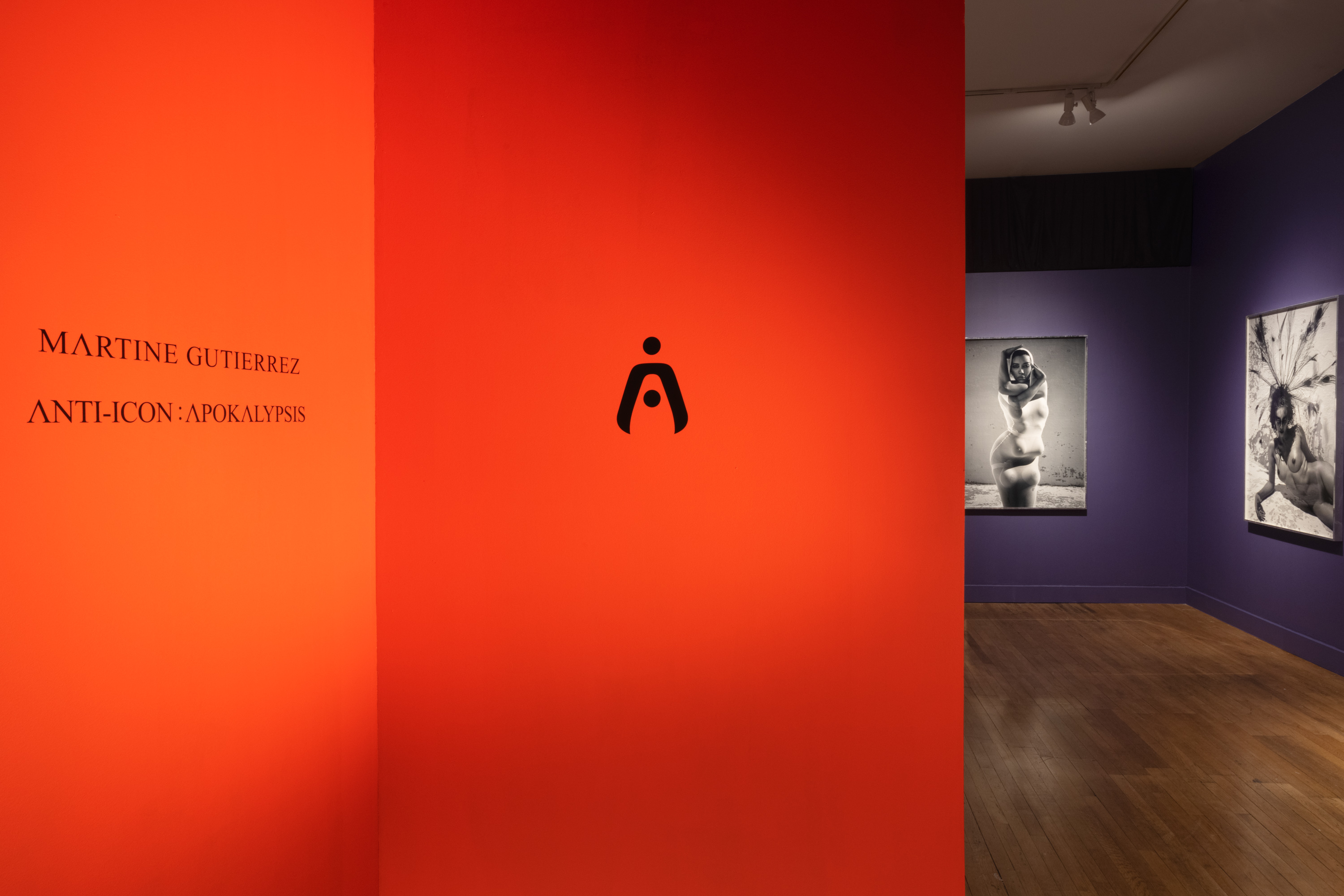 Color image of the entryway into an exhibition with large scale black and white photographs on purple wall