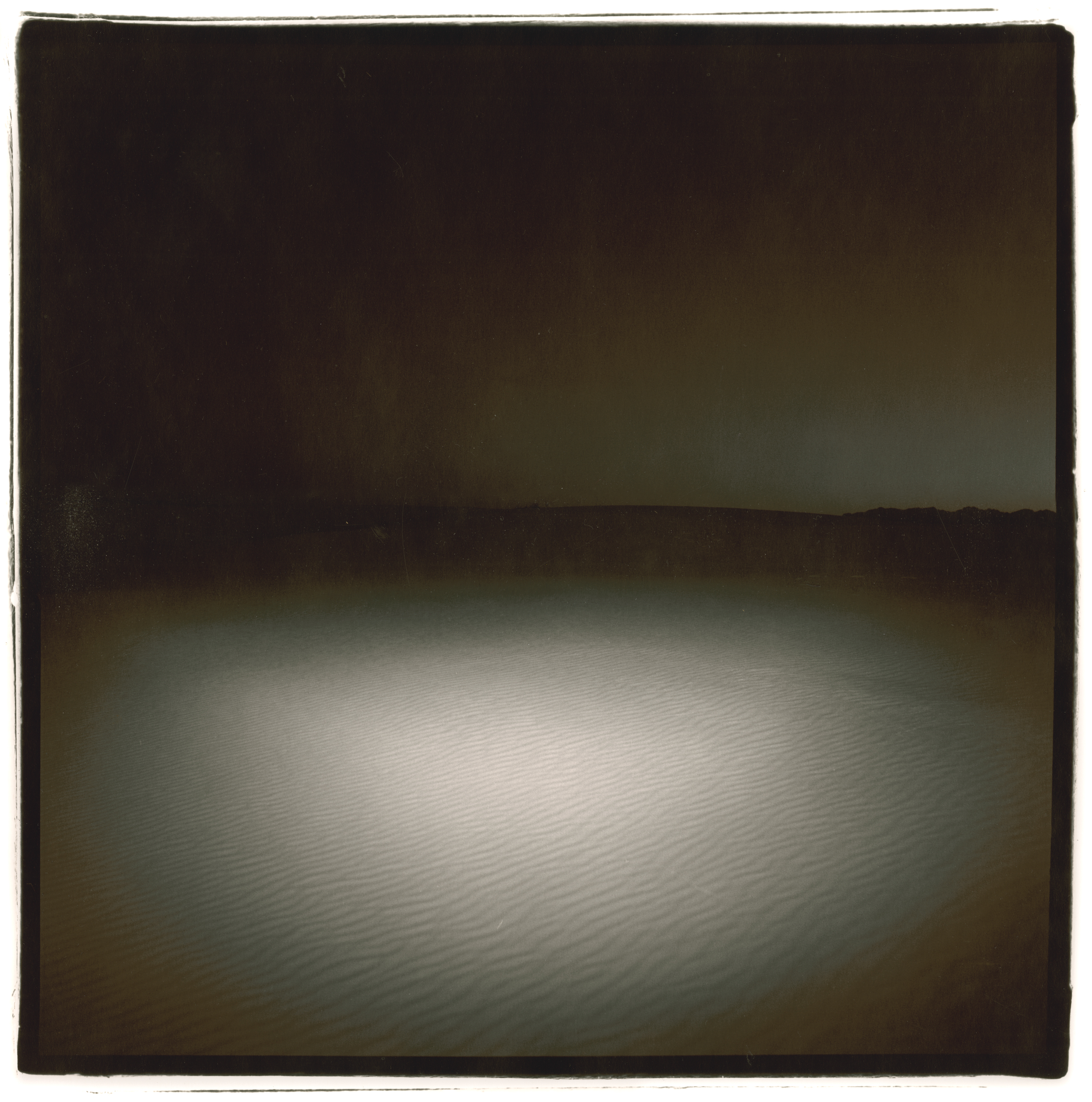 Black and white photograph of an empty desert at night with black borders around image