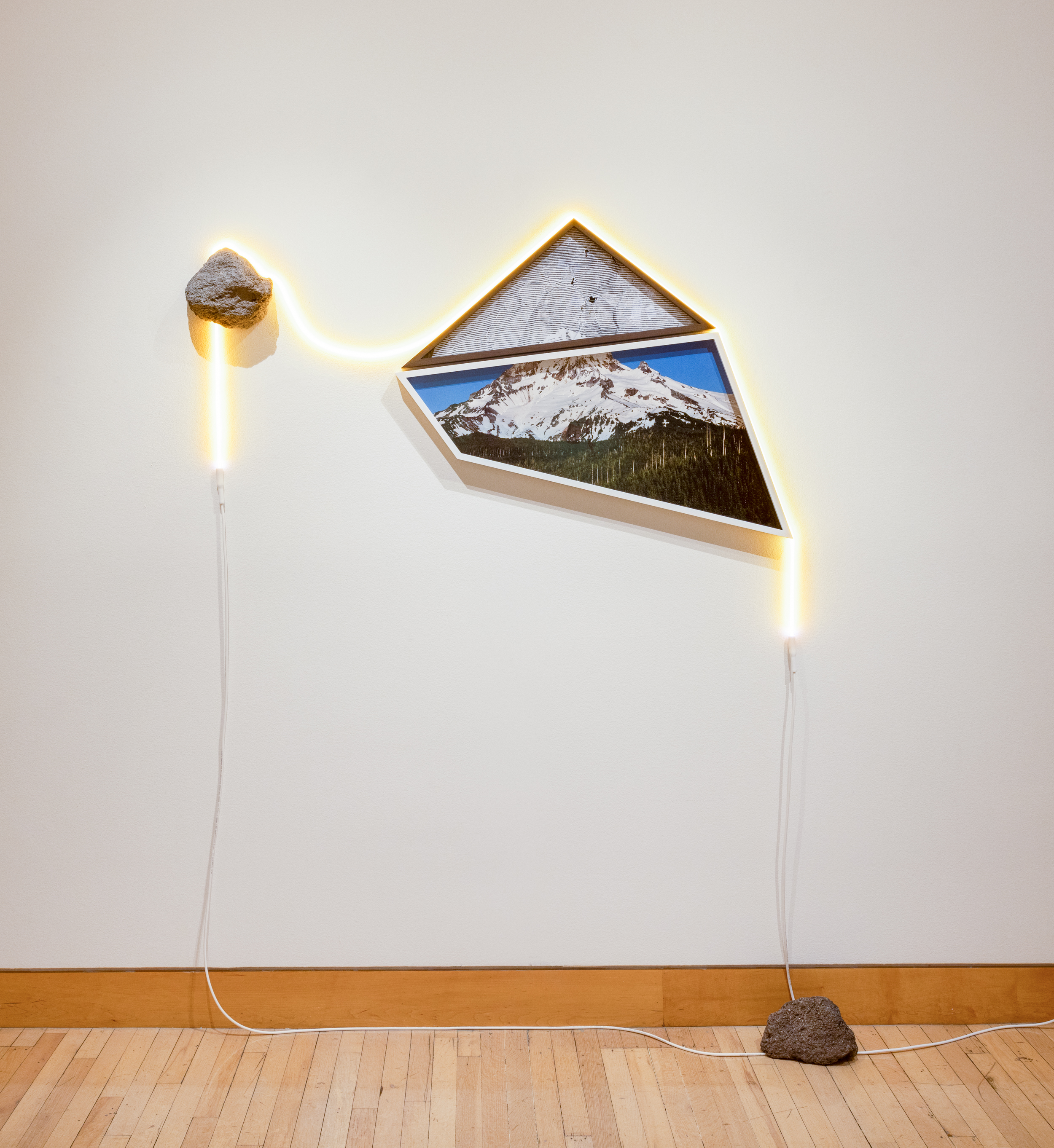 Sculpture with two rocks, a strip of neon, and two framed images