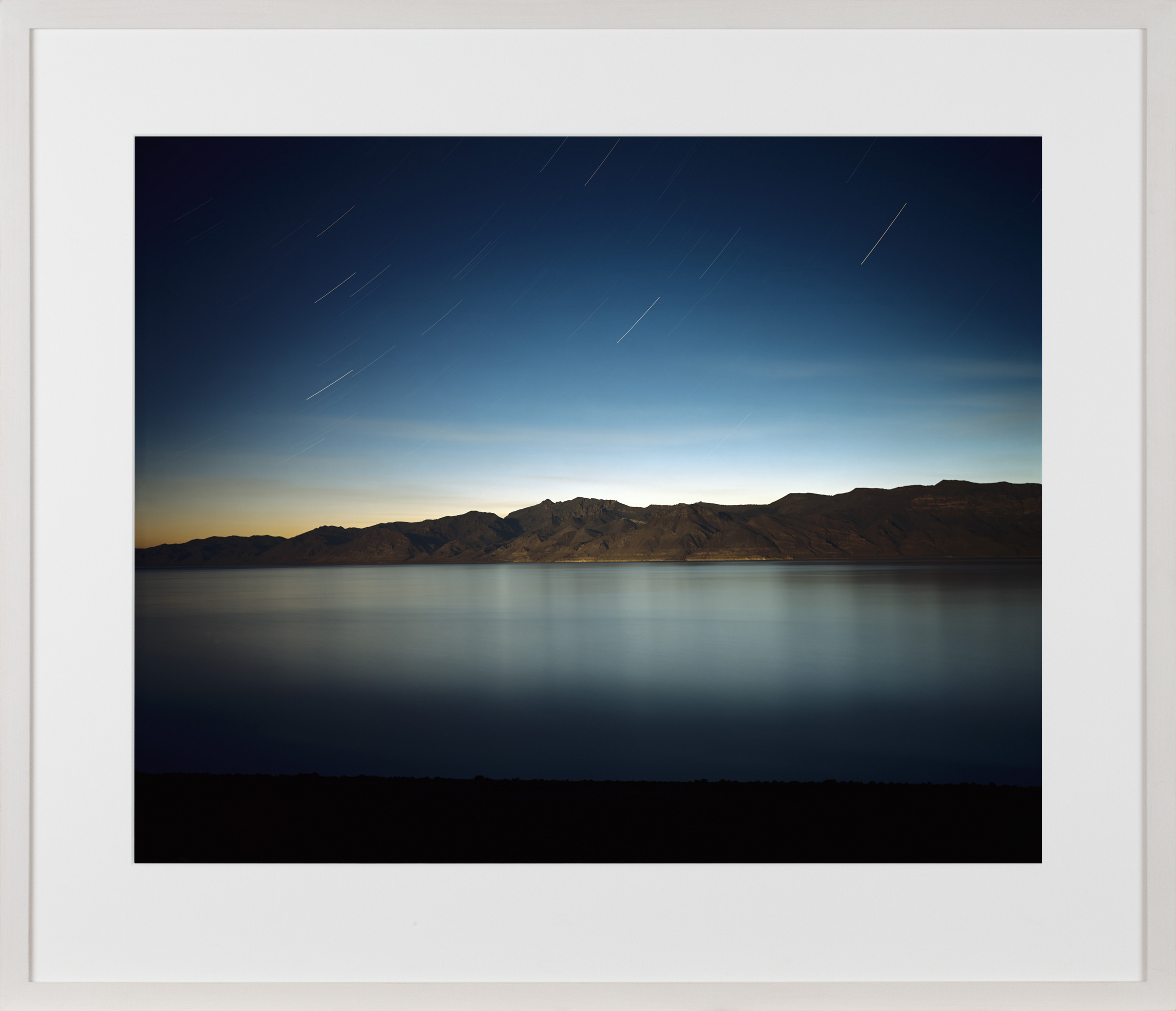 Color image of a color photograph of a lake within a desert amongst the stars framed in white