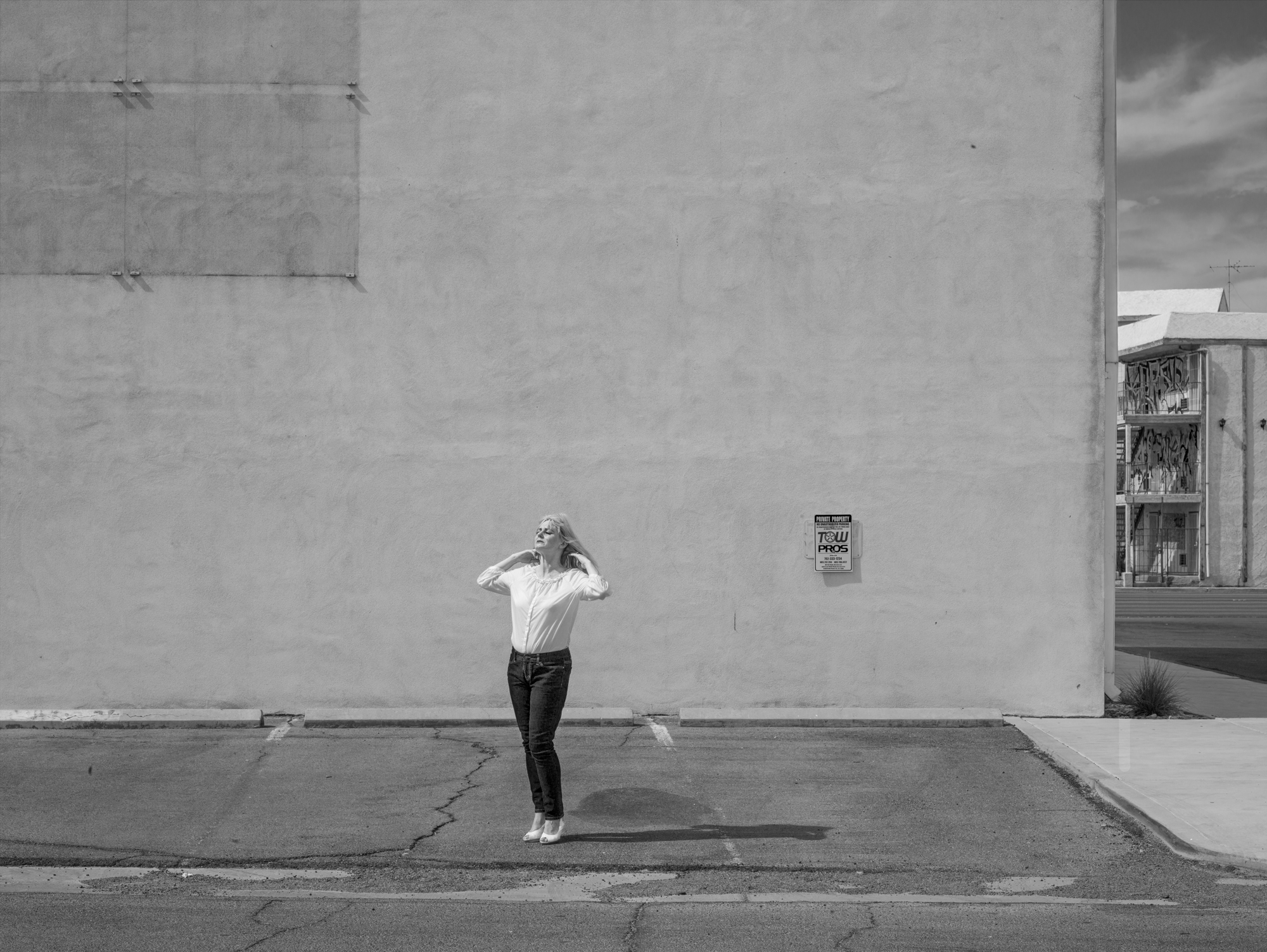 Black and white photograph of figure posing in an empty parking lot