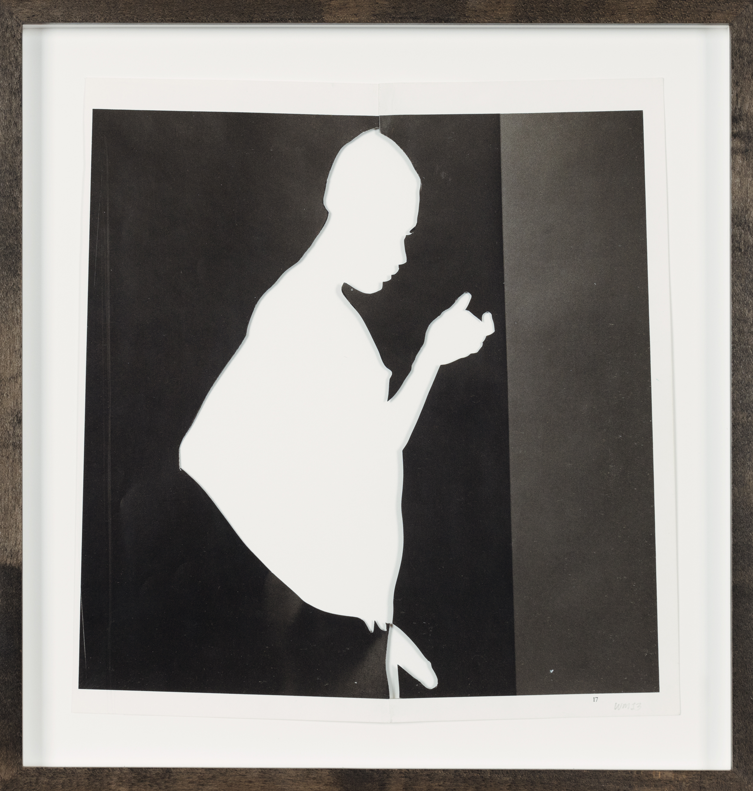 Color image of a black and white collage depicting a figures silhouette with negative space framed in grey stained maple frame