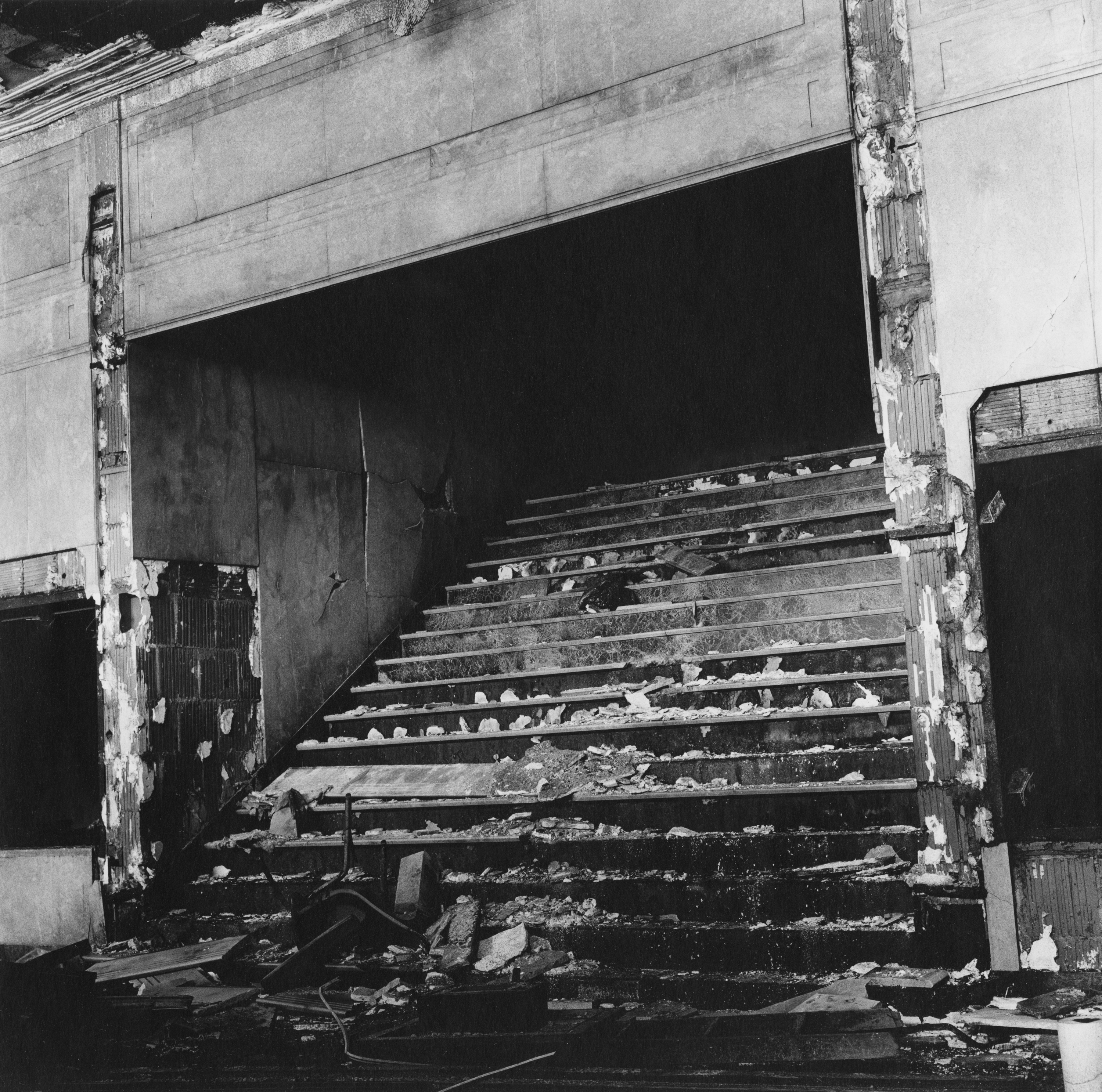 Black and white photograph of a distressed and litter ridden staircase