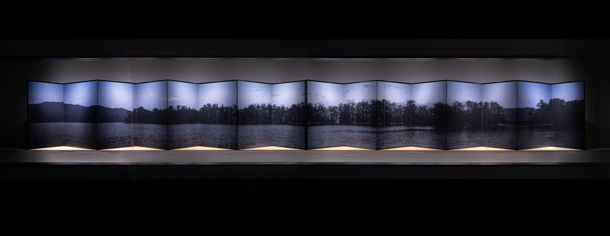 Installation view of a color photograph featuring a landscape mounted on a folding screen
