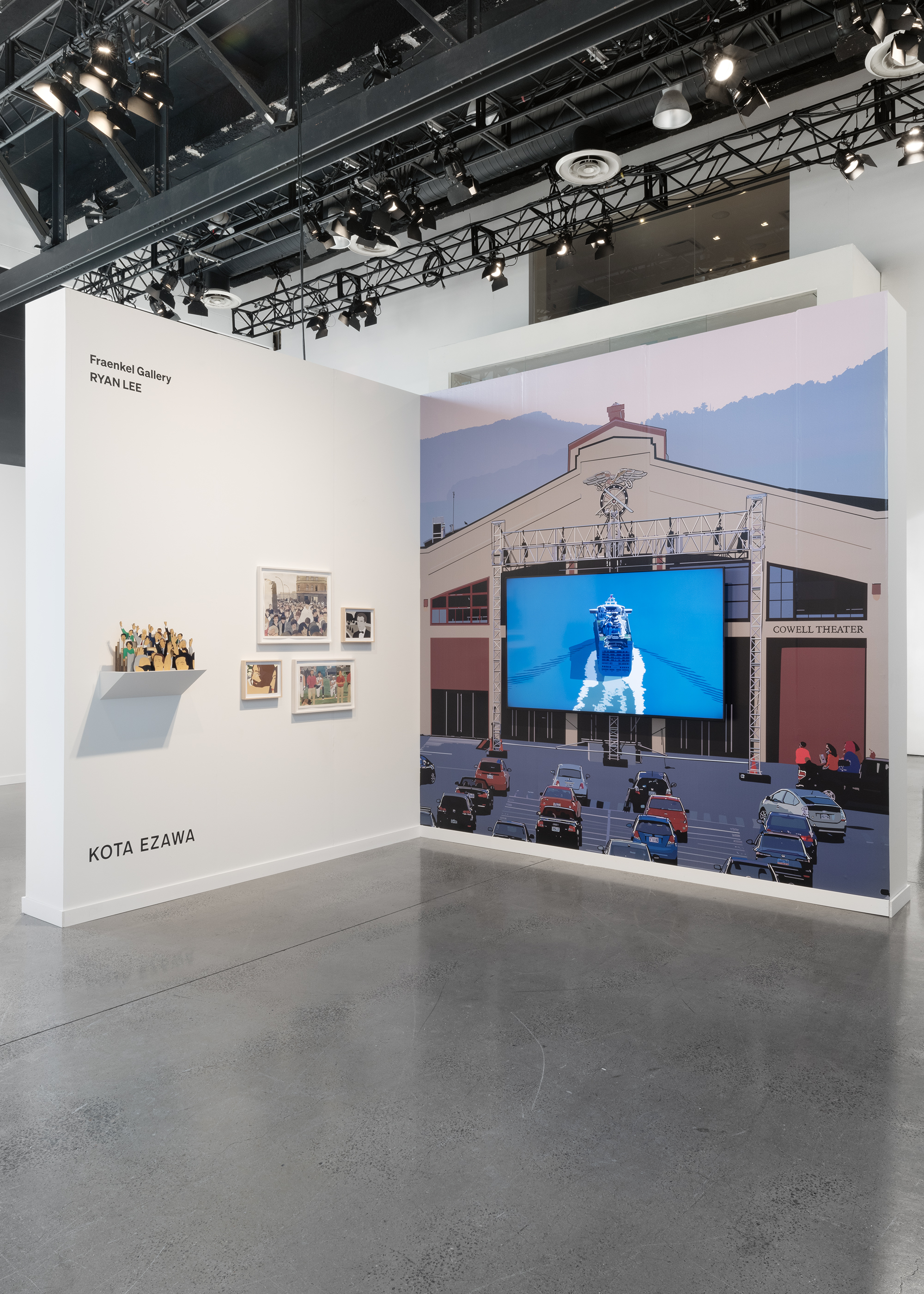 Color image of an installation of works on paper, a small sculpture, and a large video installation with wall vinyl