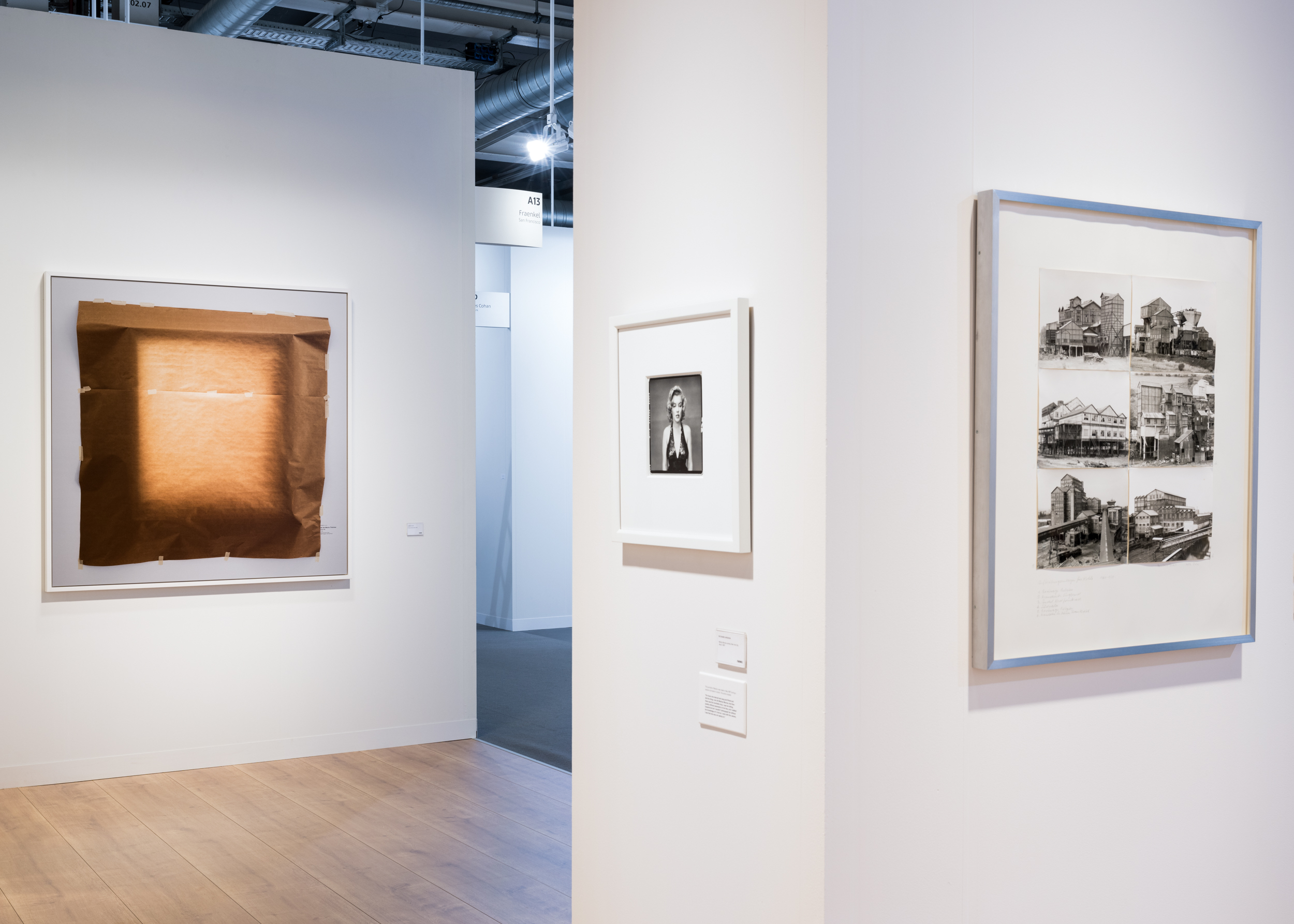 Color image of three artworks on white walls in an art fair booth